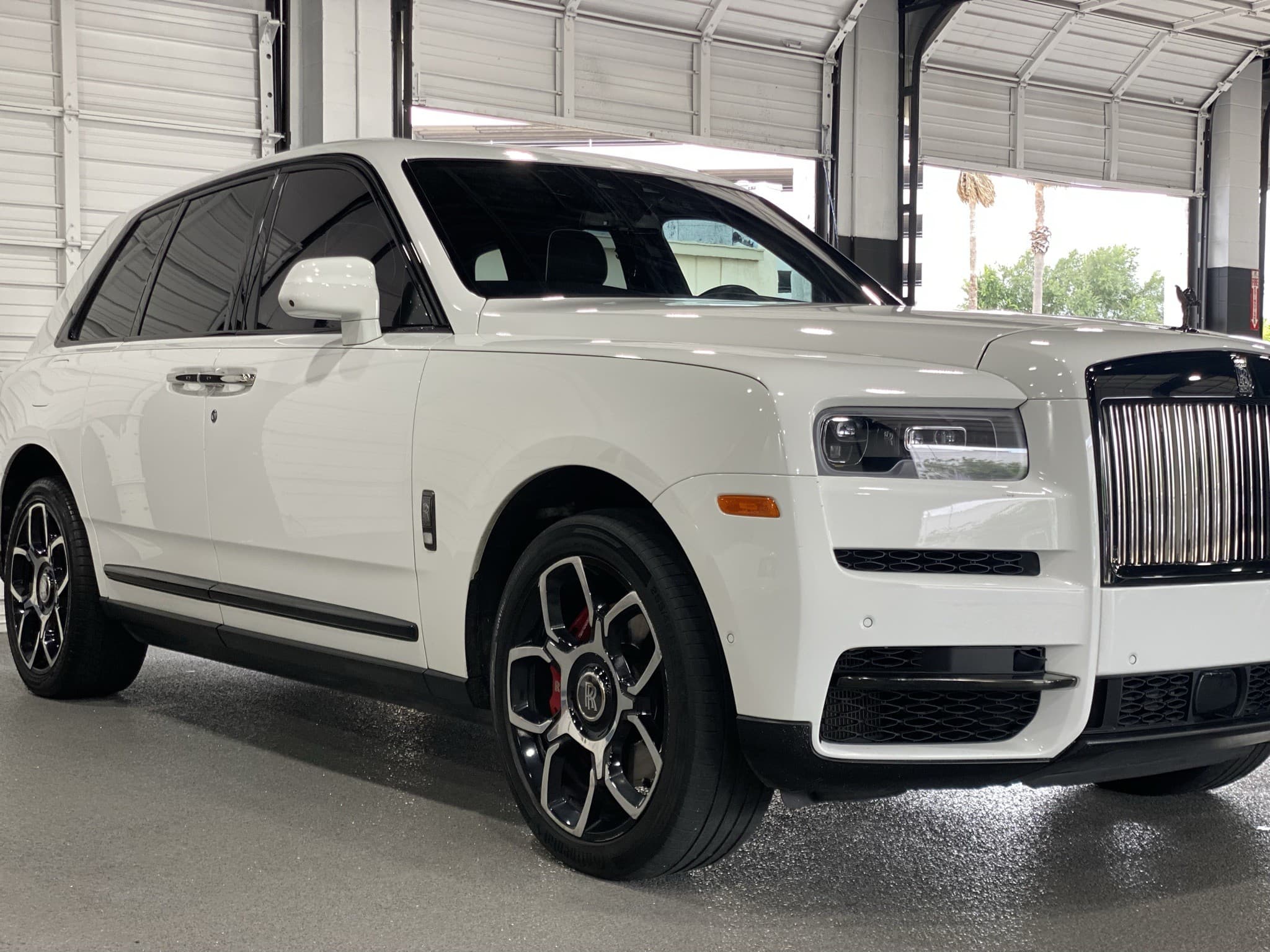 White Rolls-Royce Cullinan Black Badge front three-quarter, garage backdrop